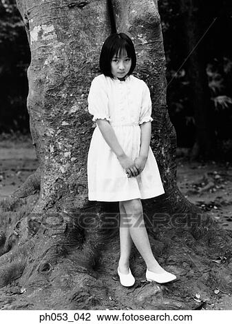 Young girl leaning against tree trunk, portrait View Large Photo Image Stock Image - Young girl leaning against tree trunk, portrait. Fotosearch