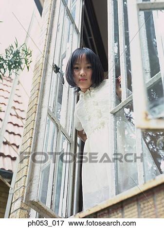 Young girl standing by open window View Large Photo Image Stock Photo - Young girl standing by open window. Fotosearch