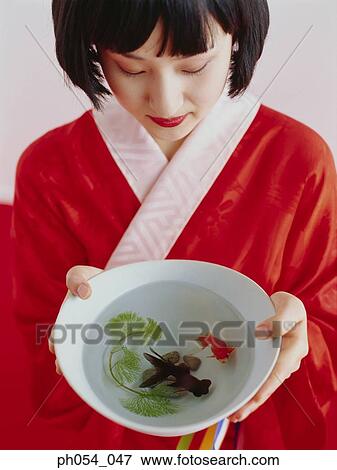 Stock Photo - Japanese woman in kimono and two goldfish in bowl. Fotosearch