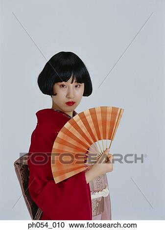 Stock Image - Japanese woman in kimono, holding a paper fan. Fotosearch