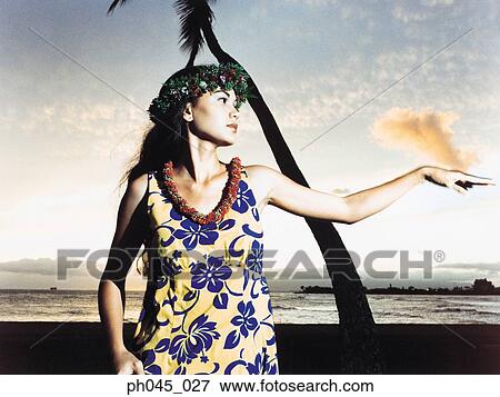 Stock Photo - A female hula dancing outdoors near the ocean at sunset. Fotosearch