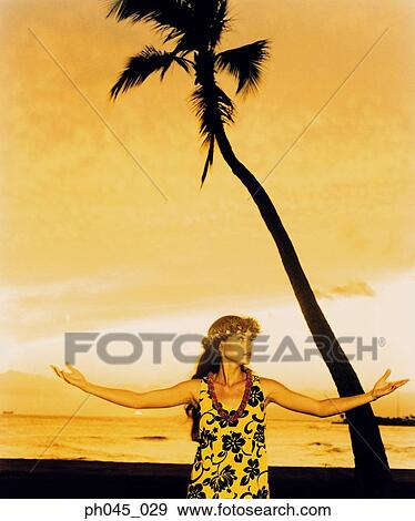 Stock Photo - A female hula dancing outdoors near the ocean at sunset. Fotosearch
