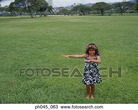Stock Image - Little hula girl dancing at the field. Fotosearch