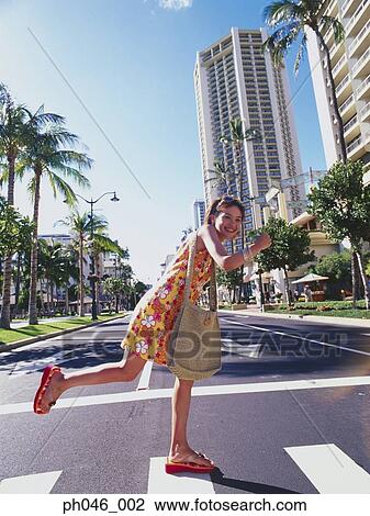 Stock Image - Young woman crossing street, Hawaii. Fotosearch