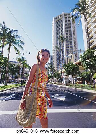 Stock Image - Young woman crossing street, Hawaii. Fotosearch