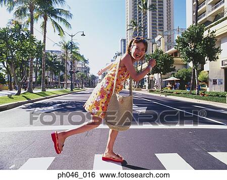Stock Photograph - Young woman crossing street, Hawaii. Fotosearch