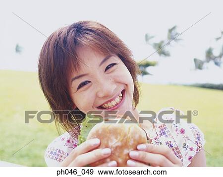 Young woman eating hamburger View Large Photo Image Stock Photo - Young woman eating hamburger. Fotosearch