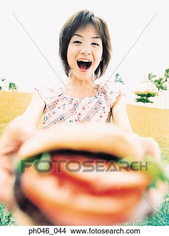 Picture - Young woman holding hamburger. Fotosearch
