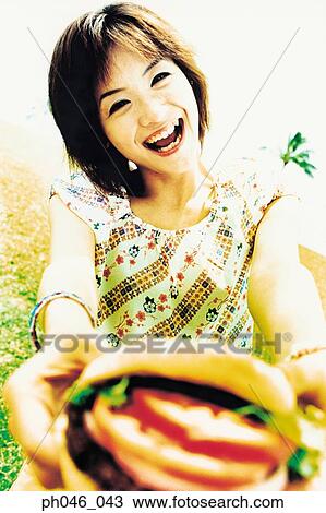 Young woman holding hamburger View Large Photo Image Stock Image - Young woman holding hamburger. Fotosearch