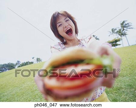 Young woman holding hamburger View Large Photo Image Stock Photo - Young woman holding hamburger. Fotosearch