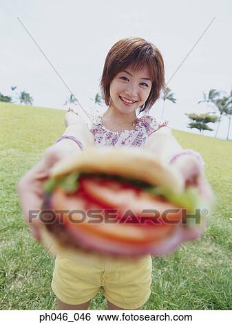 Young woman holding hamburger View Large Photo Image Stock Photograph - Young woman holding hamburger. Fotosearch