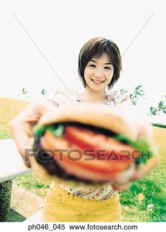 Young woman holding hamburger View Large Photo Image Stock Photography - Young woman holding hamburger. Fotosearch