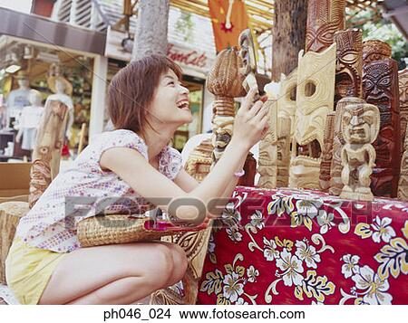 Picture - Young woman holding Hawaiian handicraft, smiling. Fotosearch