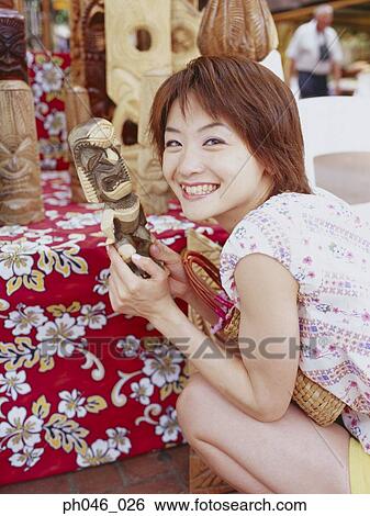 Young woman holding Hawaiian handicraft, smiling View Large Photo Image Stock Photograph - Young woman holding Hawaiian handicraft, smiling. Fotosearch