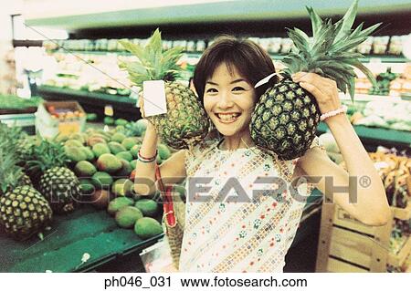 Young woman holding pineapples in fruit store View Large Photo Image Stock Image - Young woman holding pineapples in fruit store. Fotosearch