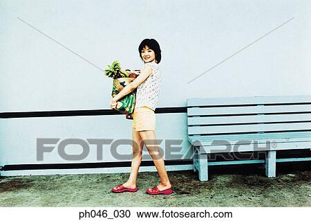 Stock Image - Young woman holding shopping bag . Fotosearch