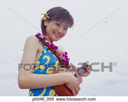 Stock Photo - Young woman in Hawaiian blouse holding ukulele . Fotosearch