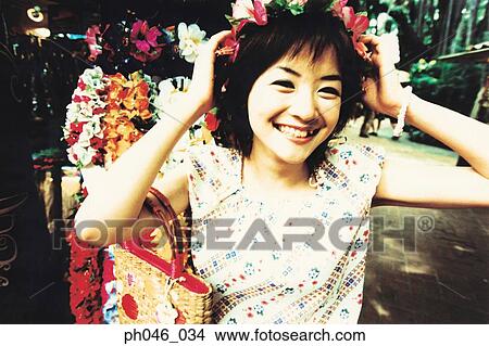 Young woman putting on garland on head View Large Photo Image Picture - Young woman putting on garland on head. Fotosearch