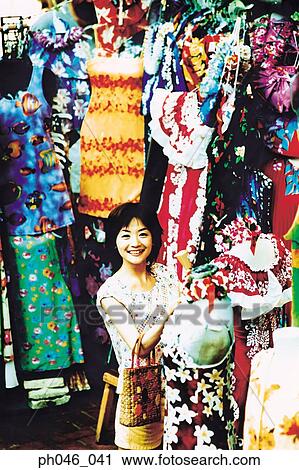 Stock Image - Young woman shopping for Hawaiian blouse. Fotosearch