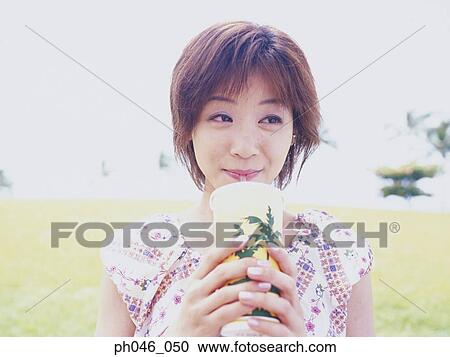 Stock Image - Young woman sipping drink from straw . Fotosearch