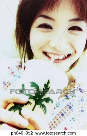Stock Image - Young woman sipping drink from straw . Fotosearch