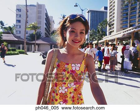 Stock Photography - Young woman smiling, urban scene in background. Fotosearch