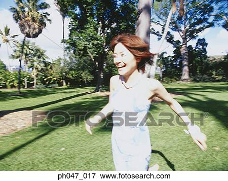 Young woman in Hawaiian blouse, running on lawn View Large Photo Image Stock Photo - Young woman in Hawaiian blouse, running on lawn . Fotosearch