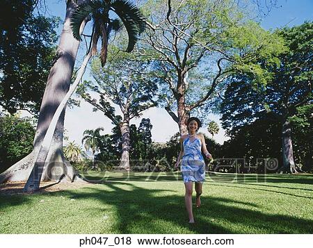 Young woman in Hawaiian blouse, running on lawn View Large Photo Image Stock Photo - Young woman in Hawaiian blouse, running on lawn . Fotosearch
