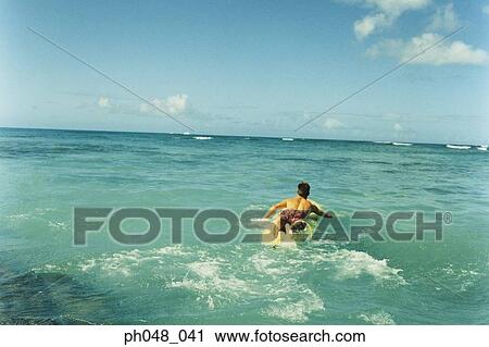 Man laying on surfboard paddling with hands in water, rear view View Large Photo Image Stock Image - Man laying on surfboard paddling with hands in water, rear view. Fotosearch
