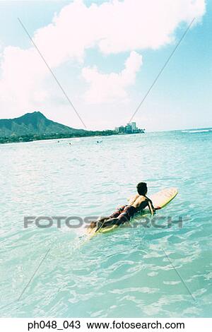 Man laying on surfboard paddling with hands in water View Large Photo Image Stock Image - Man laying on surfboard paddling with hands in water. Fotosearch
