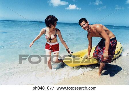 Stock Photo - Young couple pulling kayak to shore. Fotosearch