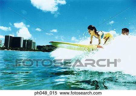 Stock Photography - Young couple surfing, Hawaii beach. Fotosearch