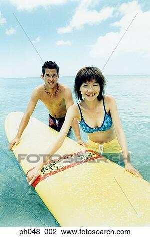 Young man and woman holding surfboard in water View Large Photo Image Stock Image - Young man and woman holding surfboard in water . Fotosearch