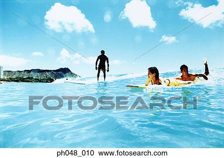 Young man and woman on surfboard in water, man surfing View Large Photo Image Stock Image - Young man and woman on surfboard in water, man surfing. Fotosearch