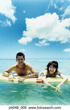 Young man and woman on surfboard in water View Large Photo Image Stock Photo - Young man and woman on surfboard in water . Fotosearch