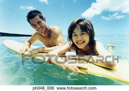 Young man and woman on surfboard in water View Large Photo Image Stock Photograph - Young man and woman on surfboard in water . Fotosearch