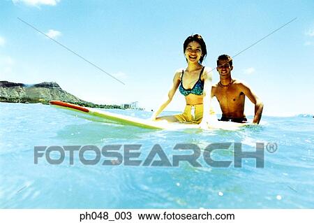 Young man and woman sitting on surfboard in water View Large Photo Image Stock Image - Young man and woman sitting on surfboard in water . Fotosearch