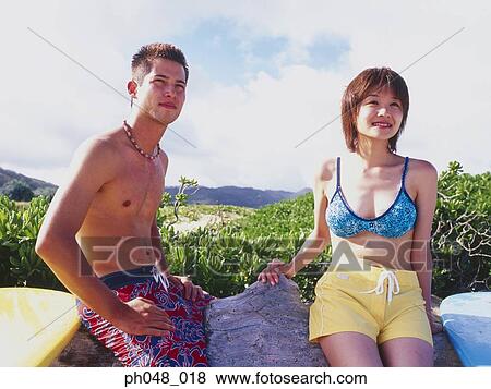 Young man and woman sitting on surfboard View Large Photo Image Stock Photo - Young man and woman sitting on surfboard. Fotosearch