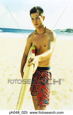 Young man at a beach, holding surfboard View Large Photo Image Stock Photography - Young man at a beach, holding surfboard . Fotosearch