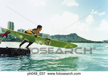 Young man jumping off with surfboard View Large Photo Image Stock Photo - Young man jumping off with surfboard. Fotosearch