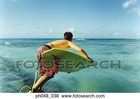 Young man jumping off with surfboard, rear view View Large Photo Image Stock Photo - Young man jumping off with surfboard, rear view. Fotosearch