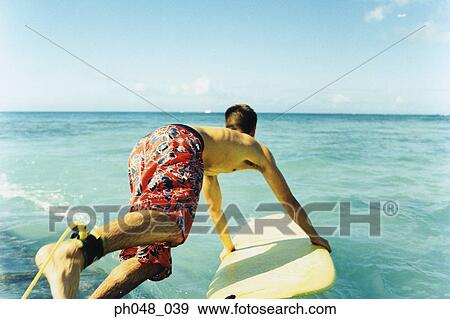 Young man jumping off with surfboard, rear view View Large Photo Image Stock Photo - Young man jumping off with surfboard, rear view. Fotosearch