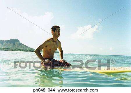 Young man sitting on surfboard View Large Photo Image Picture - Young man sitting on surfboard. Fotosearch