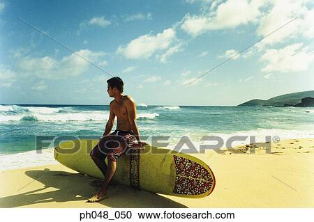 Young man sitting on surfboard View Large Photo Image Stock Image - Young man sitting on surfboard. Fotosearch