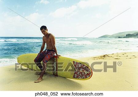 Young man sitting on surfboard View Large Photo Image Stock Image - Young man sitting on surfboard. Fotosearch