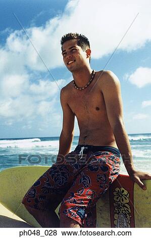Stock Photo - Young man sitting on surfboard. Fotosearch