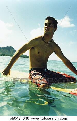 Young man sitting on surfboard View Large Photo Image Stock Photograph - Young man sitting on surfboard. Fotosearch