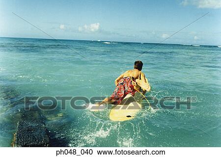 Stock Image - Young man with surfboard, rear view. Fotosearch