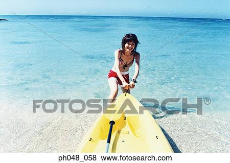 Young woman pulling sea kayak into water View Large Photo Image Stock Photo - Young woman pulling sea kayak into water . Fotosearch