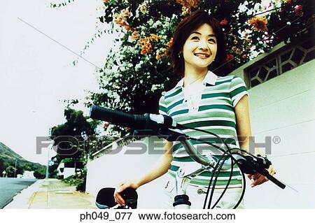 Stock Photo - Woman with bicycle, smiling. Fotosearch
